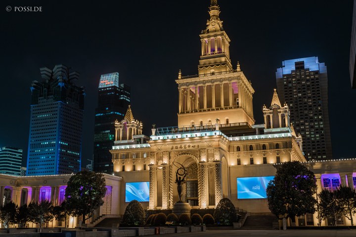 Das Bild zeigt ein beeindruckendes Gebäude in Shanghai, das mit seinen goldenen Lichtern und der Skyline im Hintergrund eine majestätische Atmosphäre ausstrahlt. (29.03.2025)