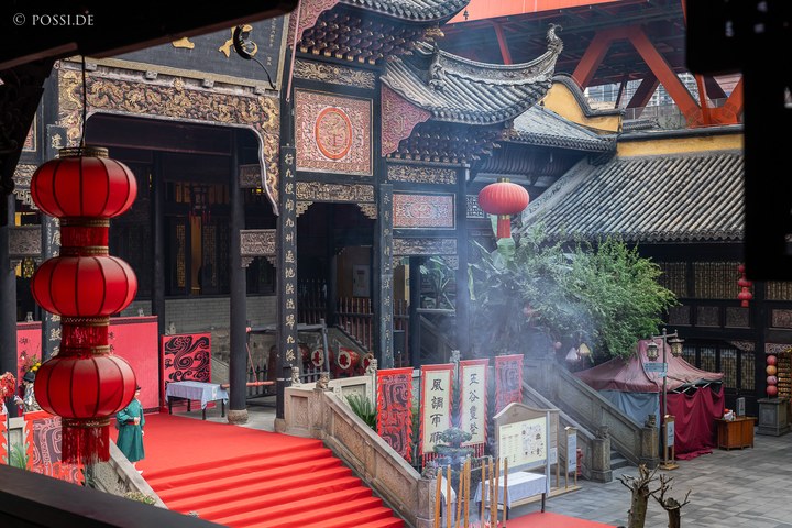 Das Bild zeigt eine chinesische Tempelanlage mit roten Laternen und einem roten Teppich, der zu einer Treppe führt. (03.04.2025)