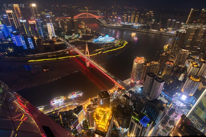 Die Stadtansicht zeigt eine beleuchtete Skyline mit hohen Gebäuden und Brücken, die über einen Fluss führen. (04.04.2025)