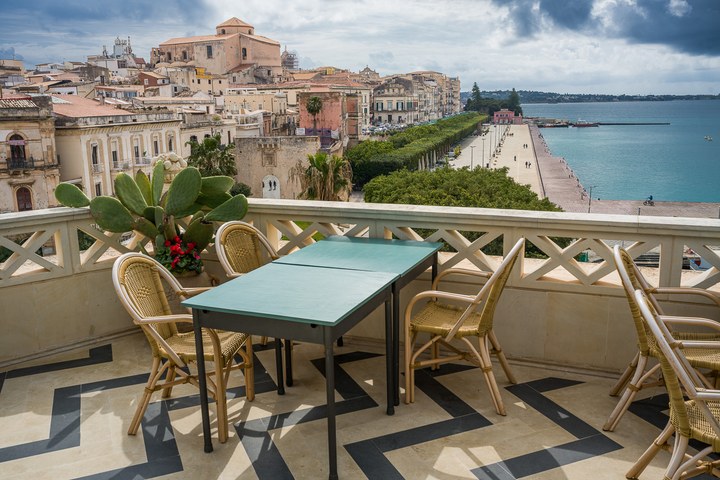Das Bild zeigt eine Terrasse mit einem Tisch und Stühlen, die einen atemberaubenden Blick auf das Meer bietet. (06.03.2026)